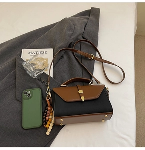 Détail d'un sac à main bicolore vintage marron et noir avec fermoir doré et bijou de sac