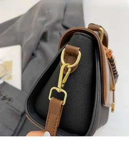 Gros plan sur la boucle en métal doré et la bandoulière en cuir marron du sac