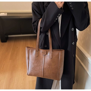 Dettaglio della borsa tote vintage in pelle marrone con cuciture e tracolla sottile