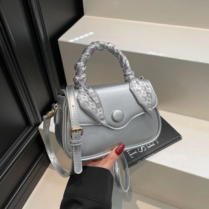 Silver square crossbody bag with silk scarf handle on minimalist display stand