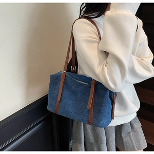 Detail of blue denim shoulder bag with brown leather straps and adjustable buckles