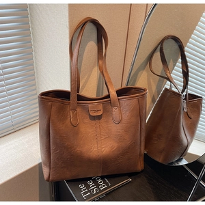 Dettaglio di una borsa tote marrone con trama vintage e logo Fashion Trend in pelle