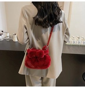 Detail of red plush crossbody bucket bag with bow tie and leather strap on model