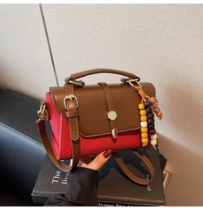 Détail du sac en toile rouge avec accents en cuir marron et breloque en perles