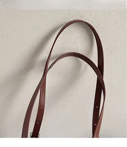 Detail of adjustable brown leather shoulder strap with refined stitching for a crossbody bag
