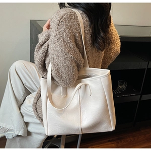 Borsa tote in ecopelle color crema con doppie tracolle indossata in un ambiente interno