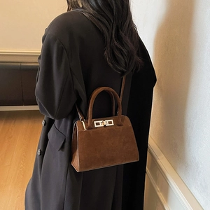 Detailed shot of dark brown matte leather texture and silver metal twist lock on handbag