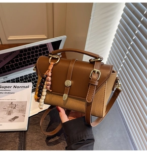 Détail du sac rétro en cuir et toile avec breloque perlée et boucles en laiton