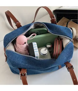 Detail view of denim shoulder bag interior with daily essentials like purse and notebook