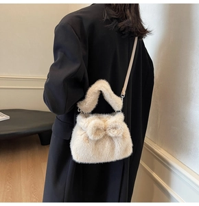 Detail of plush cream bucket bag with faux rabbit fur bow and thin leather shoulder strap