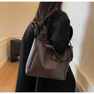Dettaglio di una borsa tote marrone scuro in pelle vintage con cuciture e texture di qualità