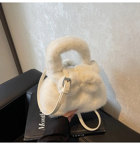 Detail of soft off-white plush bucket bag featuring a decorative bow and leather strap