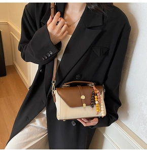 Détail du sac bandoulière en toile avec rabat en cuir et pompon en perles colorées