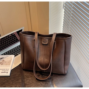 Dettaglio della borsa tote marrone scuro con trama in ecopelle vintage e logo inciso