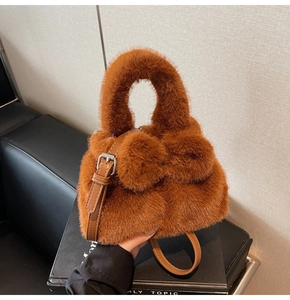 Close-up of caramel plush bucket bag with large faux fur bow and adjustable strap