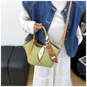 Detail of green woven handbag with leather trim and floral silk scarf accessory
