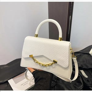 Détail du sac à main en similicuir blanc avec rabat tressé et chaîne dorée épaisse