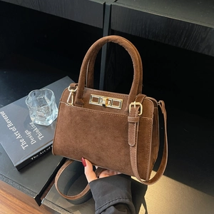 Detail of vintage matte brown leather handbag with gold metal clasp on a wooden table