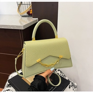 Détail du sac boîte vert clair avec texture tissée, rabat lisse et chaîne dorée chic