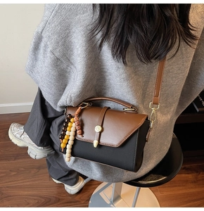 Détail d'un sac bandoulière bicolore avec perles en bois sur pull gris vue arrière