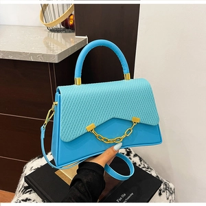 Détail du sac boîte bleu avec rabat en cuir tressé et chaîne dorée à gros maillons