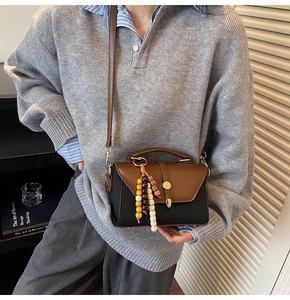 Détail du sac rétro bicolore avec pendentif en perles de bois et boucle métallique chic