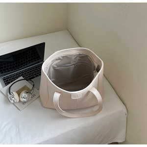 Dettaglio interno di una borsa tote beige con grande capacità e tasca con cerniera