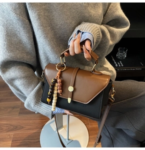 Détail du sac à main bicolore avec pompon en perles de bois colorées et anneau métallique