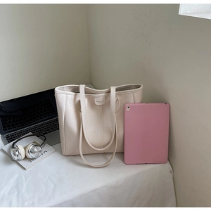 Dettaglio borsa tote in pelle PU crema con etichetta Fashion Trend su scrivania