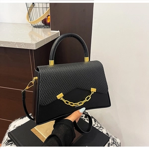 Détail du sac boîte noir en similicuir avec rabat tressé et chaîne dorée chic