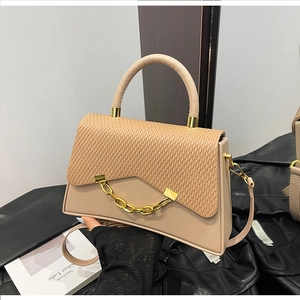 Détail du sac boîte beige montrant le contraste de texture et la chaîne dorée