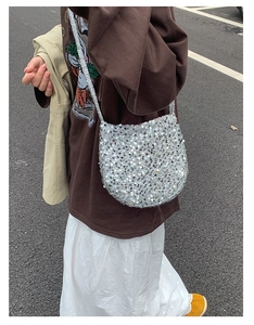 Detail einer funkelnden silbernen Pailletten-Rundtasche mit metallischer Textur im Freien