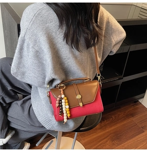 Détails d'un sac carré en toile rouge avec cuir marron, boucle métal et bijou de sac