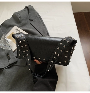 Detail of black rectangular shoulder bag featuring silver studded rivets and chic metal hardware