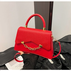 Détail du sac à main rouge en cuir avec rabat tressé et chaîne métallique dorée