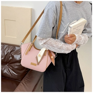 Close-up of pink and white woven bag with brown leather strap and decorative silk scarf