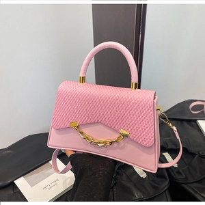 Détail du sac boîte rose en similicuir avec rabat tissé et décor chaîne dorée