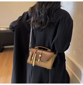 Détail du sac bandoulière en toile et cuir avec fermoir vintage et perles déco
