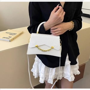 Gros plan du sac boîte en cuir blanc avec texture tissée et chaîne dorée élégante