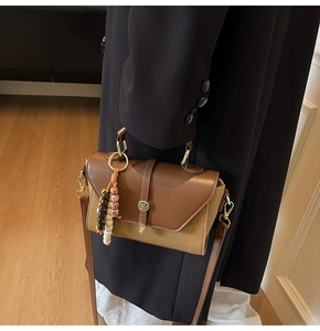 Détail du sac à main bicolore en toile et cuir avec pendentif perlé tendance