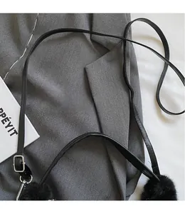 Detail of adjustable black leather strap with fluffy fur ball charm and silver metal clasp