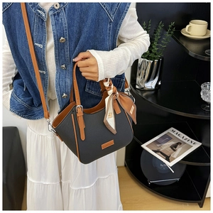 Detail of black pebbled leather bag with brown handles and a decorative printed silk scarf