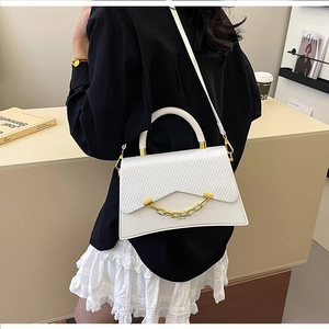 Détail du sac blanc avec texture tressée et chaîne dorée porté par un mannequin