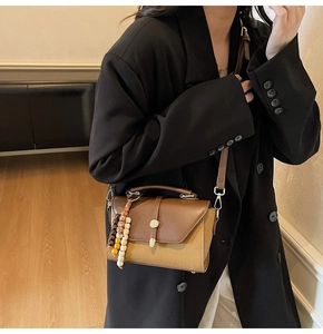 Détail du sac bandoulière vintage en cuir marron et toile avec pendentif perlé