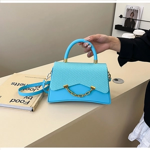 Détail du sac à main bleu sarcelle avec rabat texturé et chaîne dorée décorative