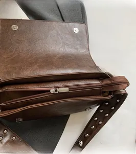 Close-up of smooth metal zipper and rivet shoulder strap on dark brown faux leather bag