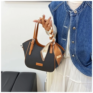 Detail of woven black handbag with brown leather trim and decorative patterned silk scarf