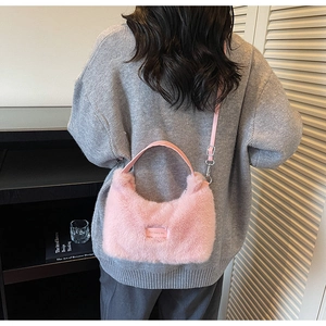 Detail of pink plush crossbody bag with leather strap worn by a model in a casual setting