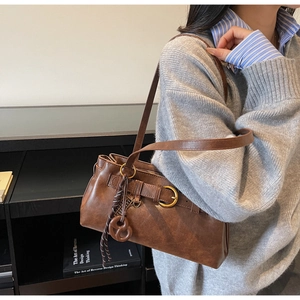 Brown vintage leather underarm bag with decorative metal buckle and woven strap detail