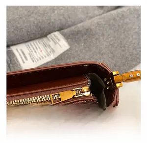Close-up of premium gold zipper and metal hardware on brown leather baguette bag
